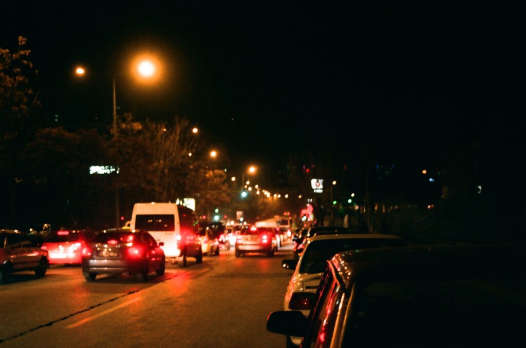 A bustling urban street filled with cars and bright streetlights at night.