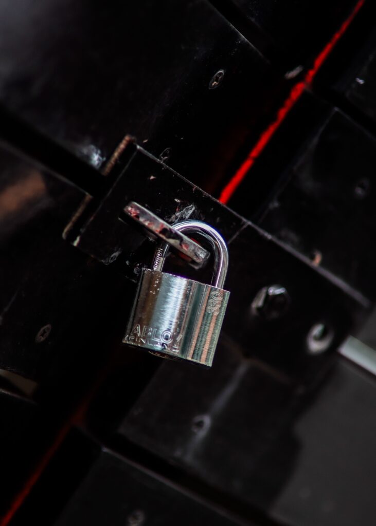 Close-up view of a metal padlock securing a dark door latch, symbolizing safety and protection.